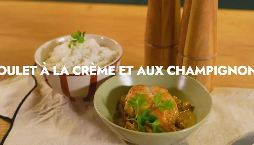Un plat de poulet aux champignons crémeux, garni de persil frais, servi avec du riz blanc.