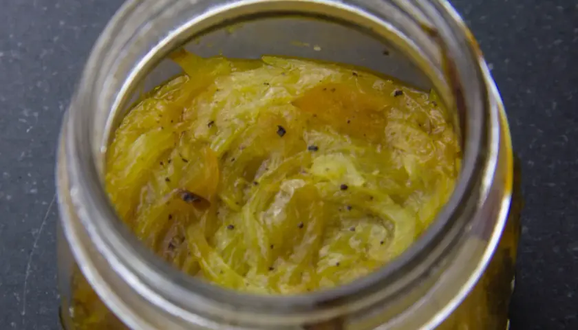 Compotée d'oignons caramélisés dans un bocal en verre, prête à être dégustée.