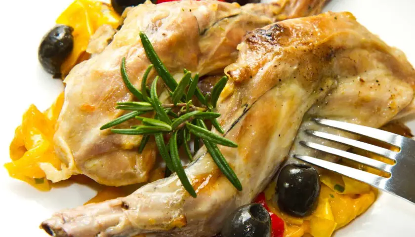 Délicieux lapin au Cookeo, servi avec des poivrons colorés, des olives noires et une touche de romarin frais.