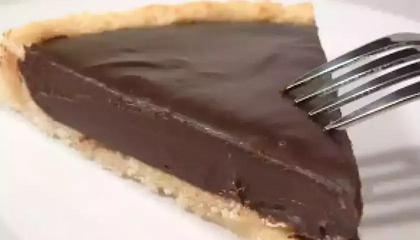 Une part de tarte au chocolat onctueuse, prête à être dégustée avec une fourchette.