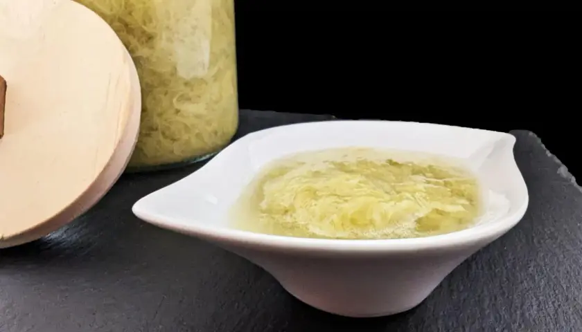 Compote de rhubarbe maison dans un bol blanc, à côté d'un bocal en verre rempli de cette délicieuse préparation.