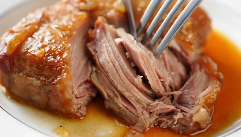 Une rouelle de porc juteuse, effilochée à la fourchette, baignant dans sa sauce dorée. Un délice pour une recette de rouelle de porc réussie.