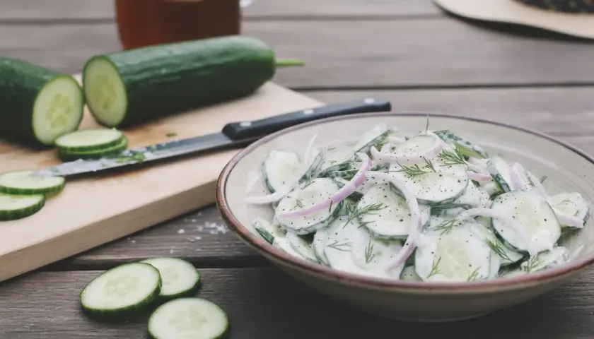 Une délicieuse salade de concombre crémeuse, garnie d'oignons rouges et d'aneth, prête à être dégustée par une chaude journée.