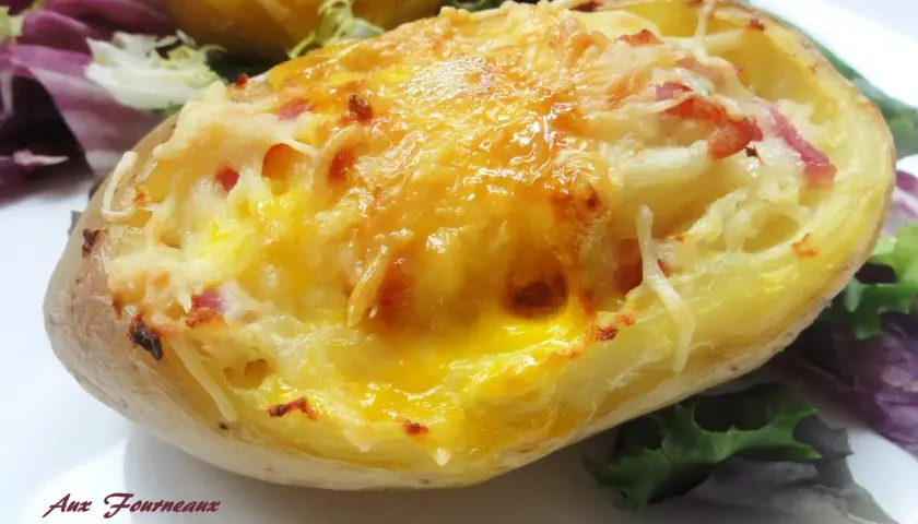 Une pomme de terre farcie, gratinée au fromage et garnie de lardons, servie avec une salade verte.