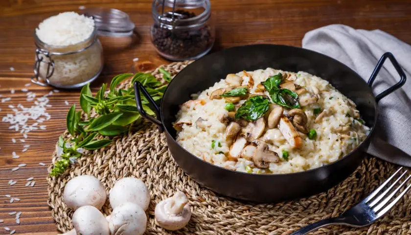 Risotto crémeux au poulet et champignons, garni de basilic frais.