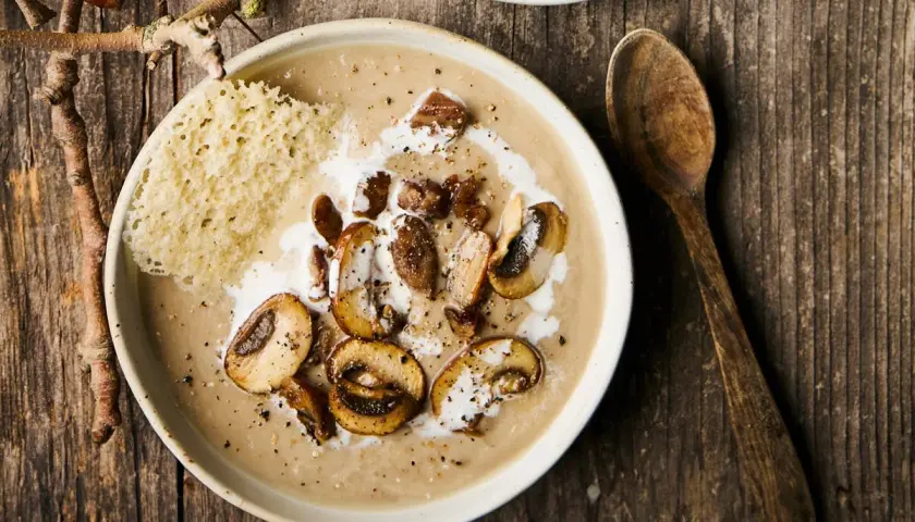 Un réconfortant velouté de champignons, garni de champignons sautés, de crème et d'une tuile de parmesan croustillante.