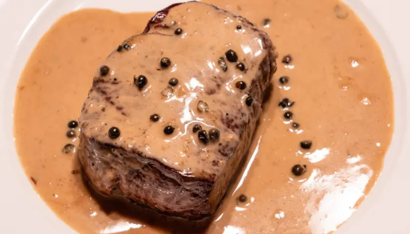 Un steak de bœuf nappé d'une onctueuse sauce au poivre, parfaite pour une recette de sauce au poivre réussie.
