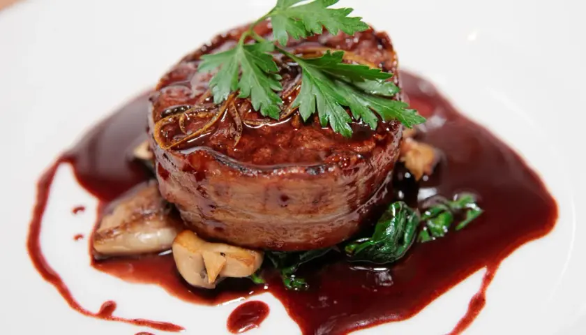 Un tendre filet de bœuf enrobé de lard, nappé d'une riche sauce marchand de vin, accompagné de champignons et d'épinards.