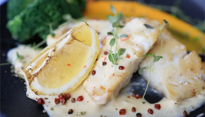 Filets de poisson nappés d'une sauce onctueuse, accompagnés d'une tranche de citron grillée et de légumes verts. Une sauce pour poisson parfaite pour sublimer ce plat.