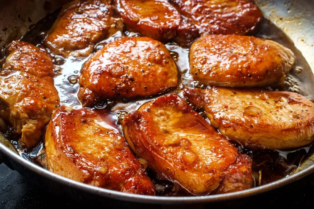 Filet mignon en train de dorer dans une poêle, baignant dans une sauce savoureuse. La marinade leur donne une belle couleur caramélisée.