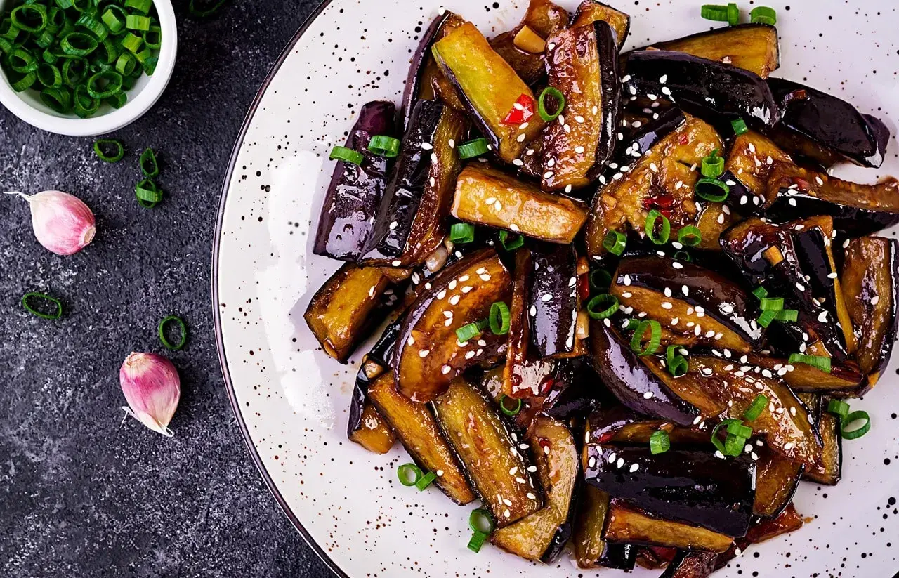 Aubergines poêlées, caramélisées et garnies de sésame et ciboule. Une recette simple et savoureuse pour sublimer ce légume.