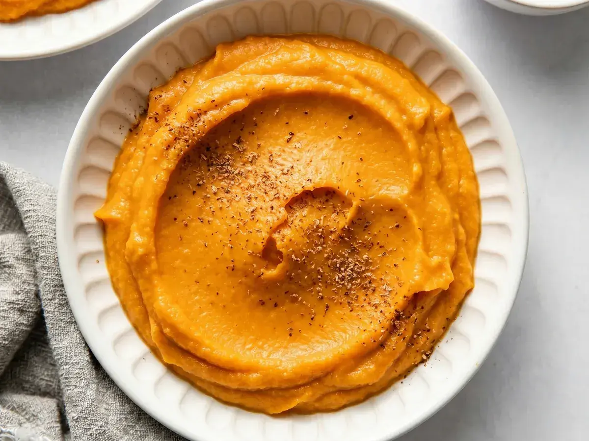 Un bol de purée de patate douce onctueuse, saupoudrée d'herbes. Un délice réconfortant.