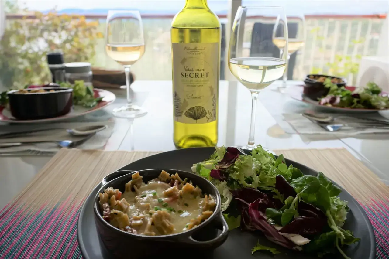Un gratin de crozet savoureux, servi avec une salade fraîche et un verre de vin blanc. Un repas simple et délicieux.