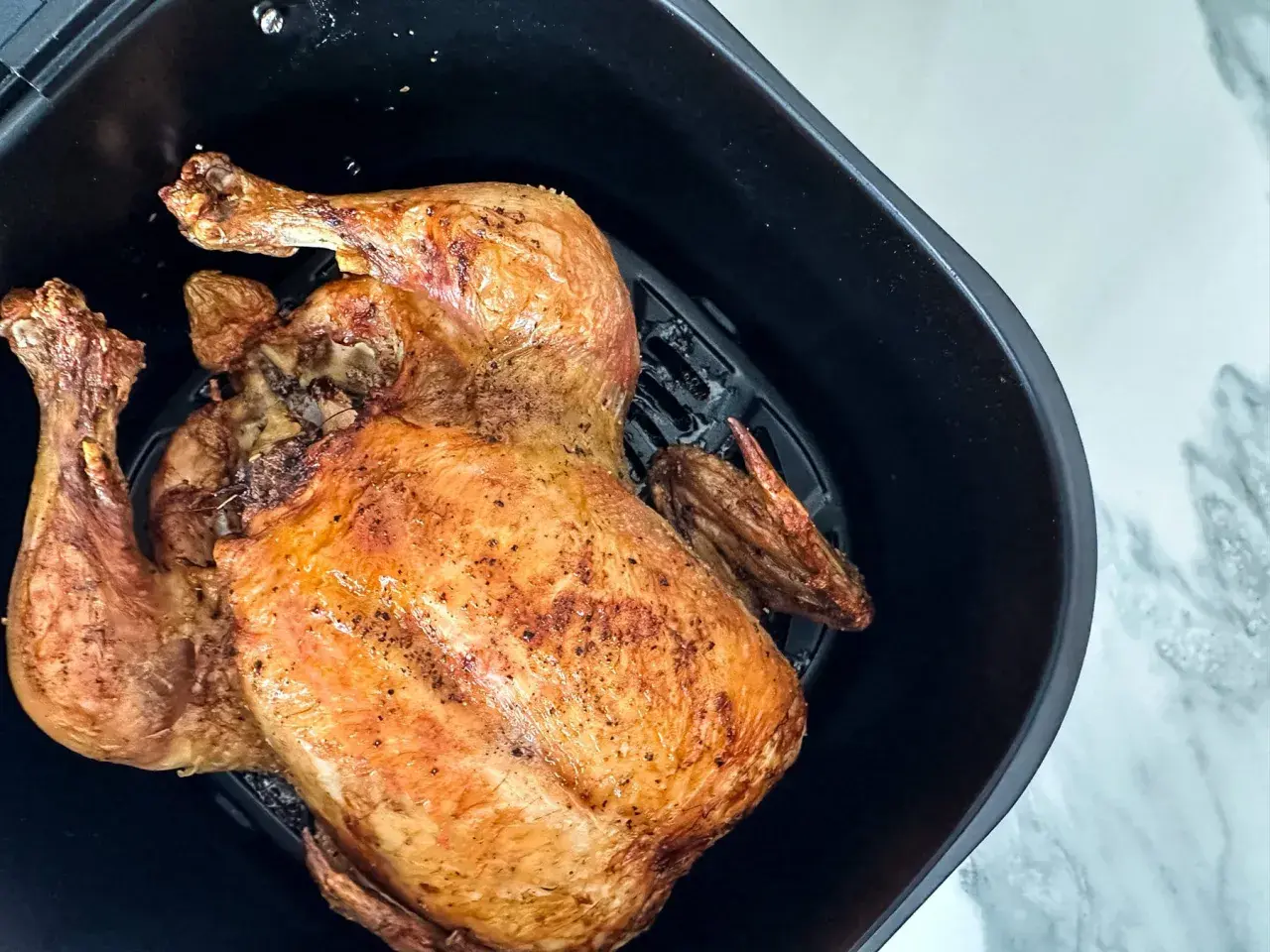 Un poulet entier doré et croustillant, tout juste sorti de l'air fryer.