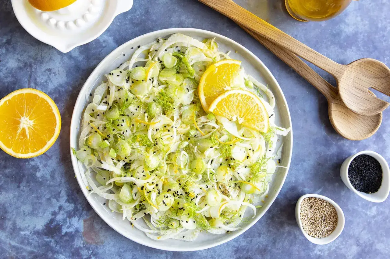 Salade de fenouil frais avec des tranches d'orange, du zeste et des graines de sésame noir. Un délice léger et croquant, parfait pour accompagner un plat.