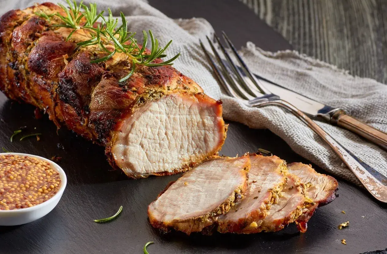 Un délicieux roti de porc Cookeo, tendre et juteux, servi avec de la moutarde à l'ancienne et des herbes fraîches.
