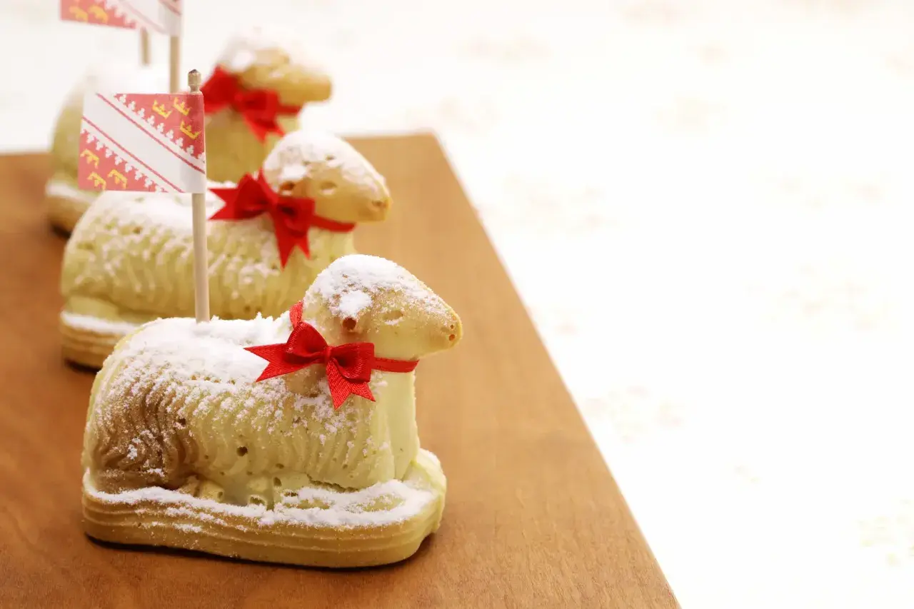 Trois agneaux en biscuit, saupoudrés de sucre glace et ornés de rubans rouges, rappellent la recette lamala grand-mère.
