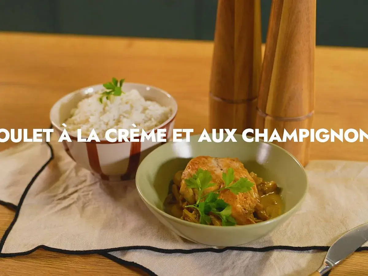 Un plat de poulet aux champignons crémeux, garni de persil frais, servi avec du riz blanc.