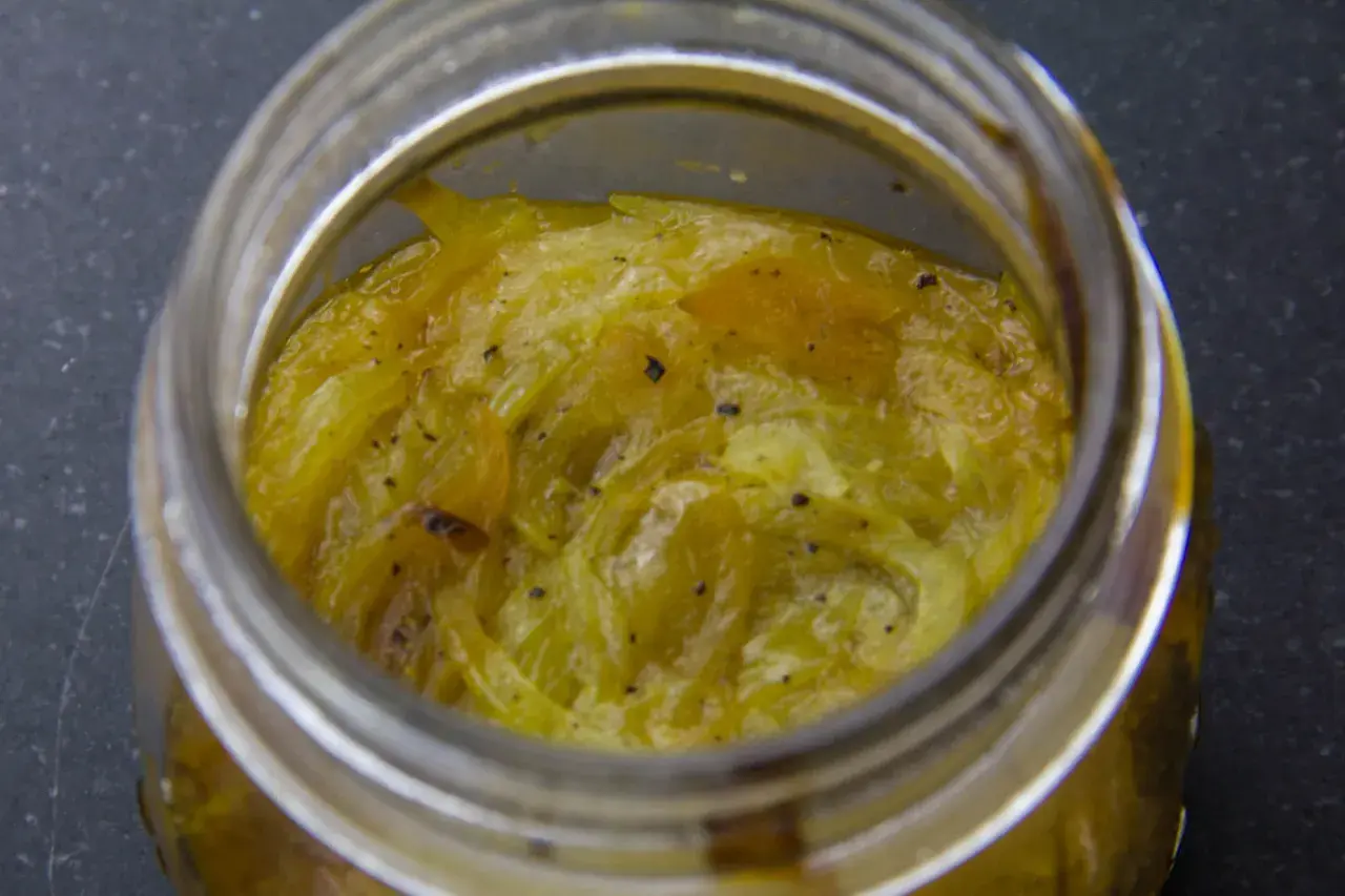 Compotée d'oignons caramélisés dans un bocal en verre, prête à être dégustée.