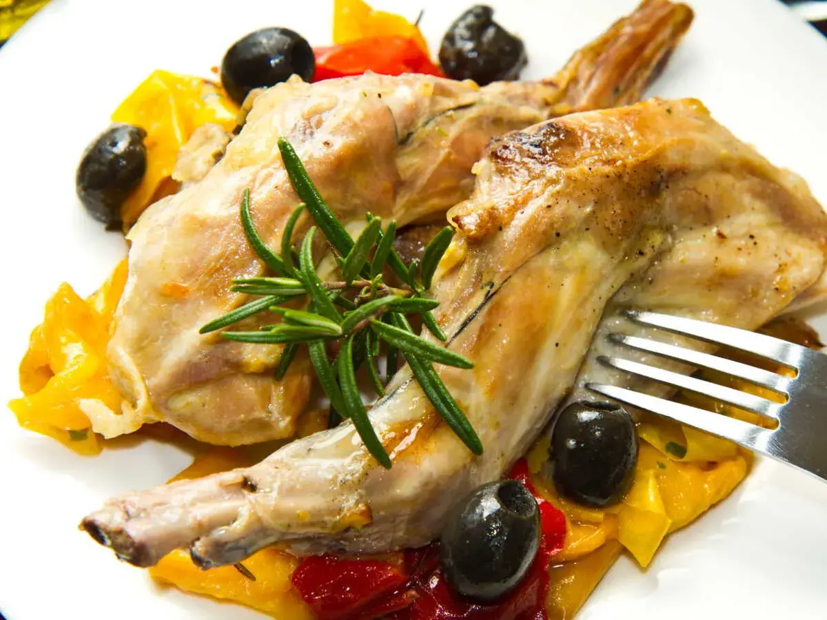 Délicieux lapin au Cookeo, servi avec des poivrons colorés, des olives noires et une touche de romarin frais.