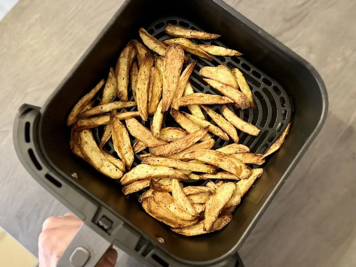 Un panier d'air fryer rempli de frites dorées et croustillantes, prêtes à être dégustées.