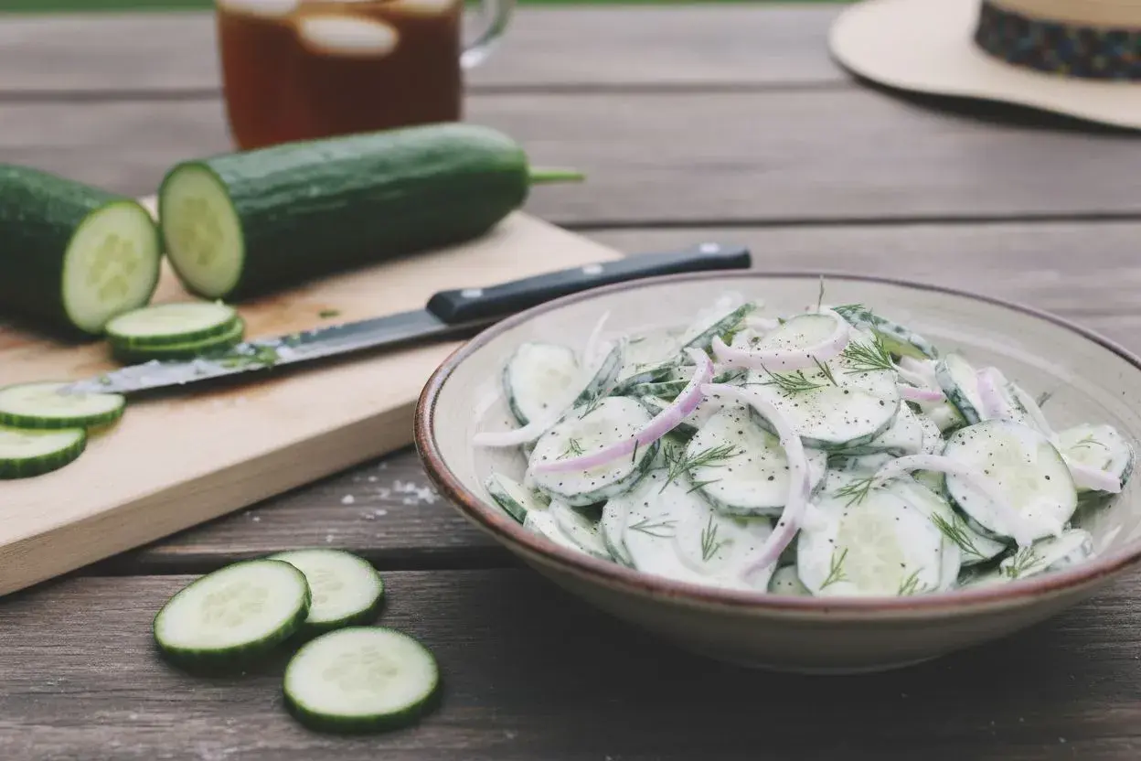Une délicieuse salade de concombre crémeuse, garnie d'oignons rouges et d'aneth, prête à être dégustée par une chaude journée.