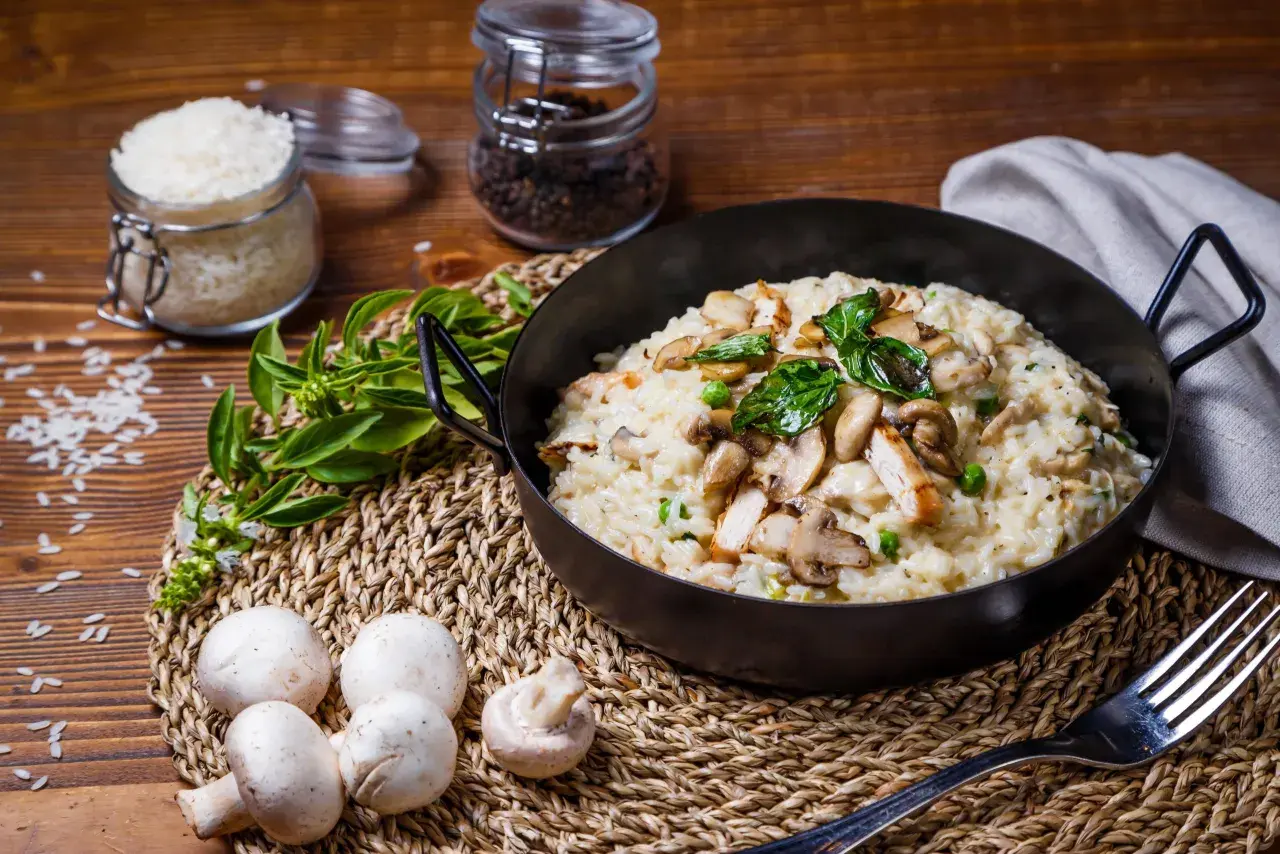 Risotto crémeux au poulet et champignons, garni de basilic frais.