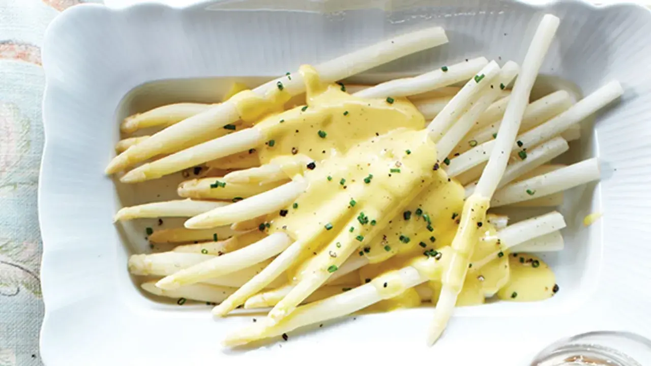 Asperges blanches tendres nappées d'une sauce crémeuse et garnies de ciboulette. Un délice printanier à déguster avec cette sauce pour asperges blanches.