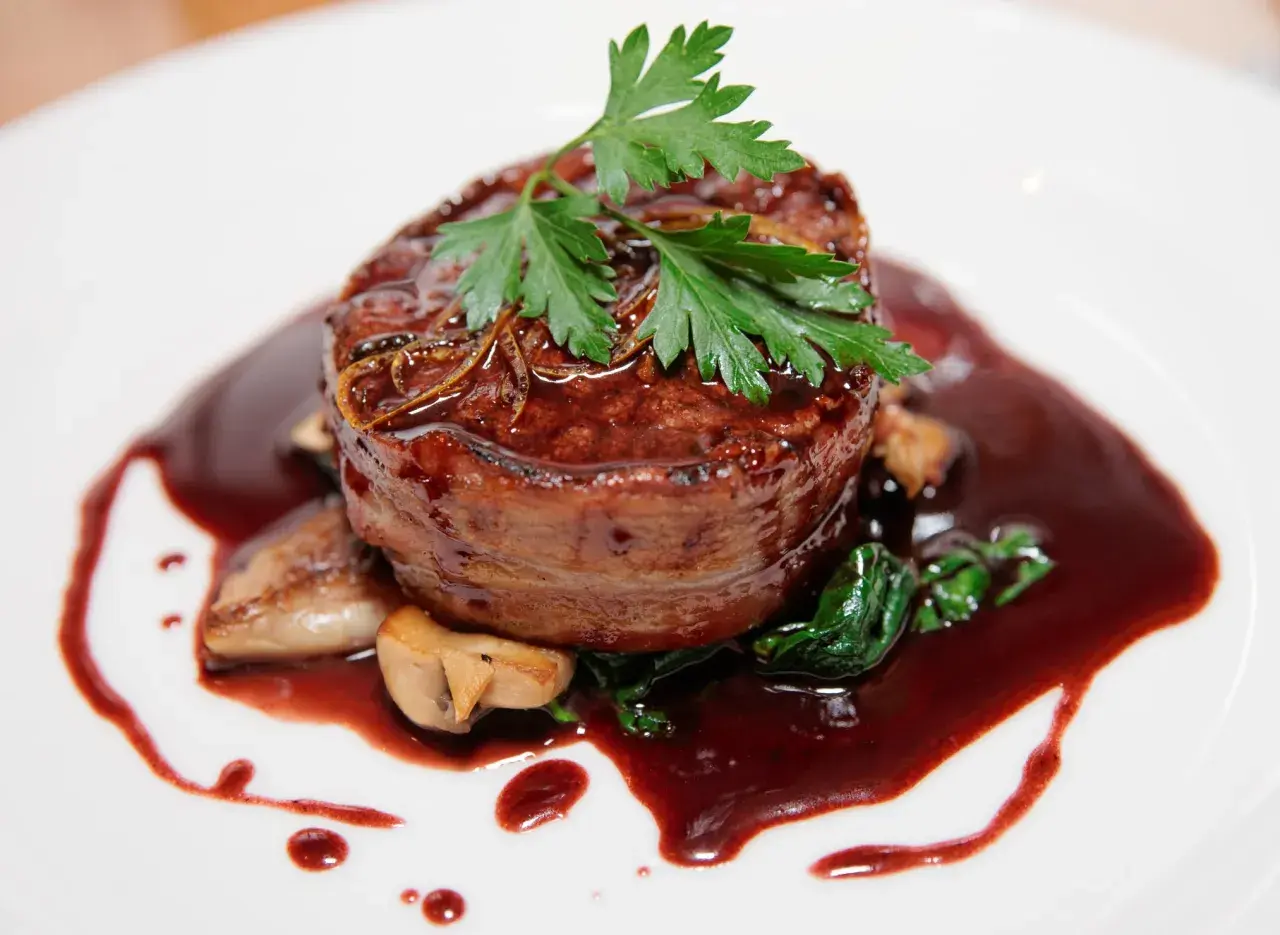 Un tendre filet de bœuf enrobé de lard, nappé d'une riche sauce marchand de vin, accompagné de champignons et d'épinards.