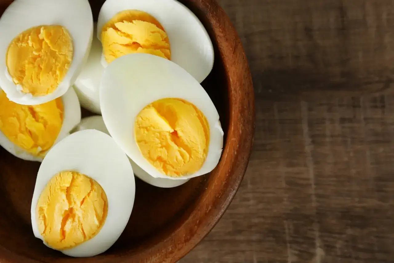 Des œufs durs coupés en deux, avec leurs jaunes dorés bien visibles, dans un bol en bois. Une recette facile à réaliser avec un oeuf dur airfryer.
