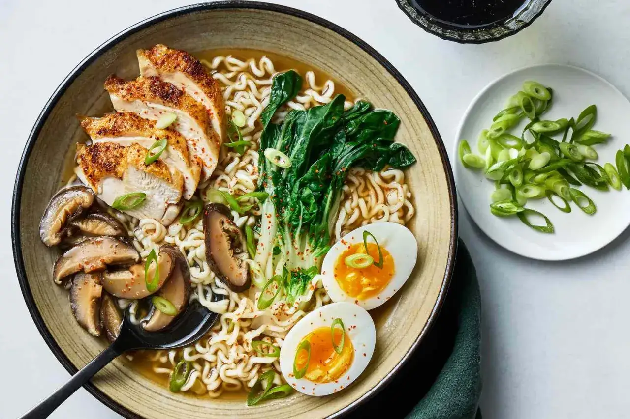 Un bol de ramen poulet savoureux avec nouilles, &oelig;uf mollet, champignons et l&eacute;gumes verts. Une recette ramen poulet parfaite pour un repas r&eacute;confortant.
