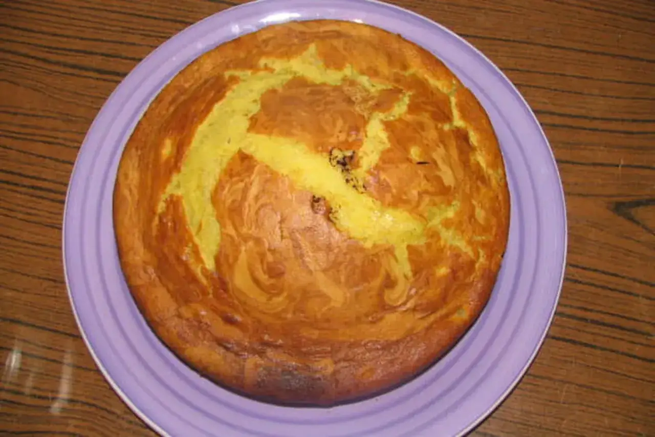 Un délicieux banana bread doré, aux marbrures jaunes et brunes, repose sur une assiette violette.