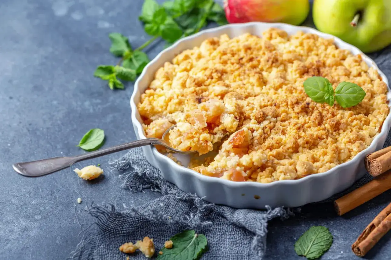 Un d&eacute;licieux p&acirc;te &agrave; crumble aux pommes, garni de menthe fra&icirc;che et de b&acirc;tons de cannelle.