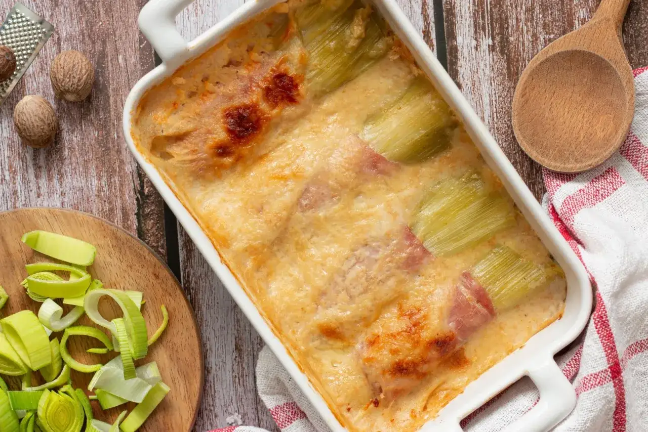 Gratin de poireaux au jambon, doré et fondant, prêt à être dégusté. Une recette réconfortante et savoureuse.