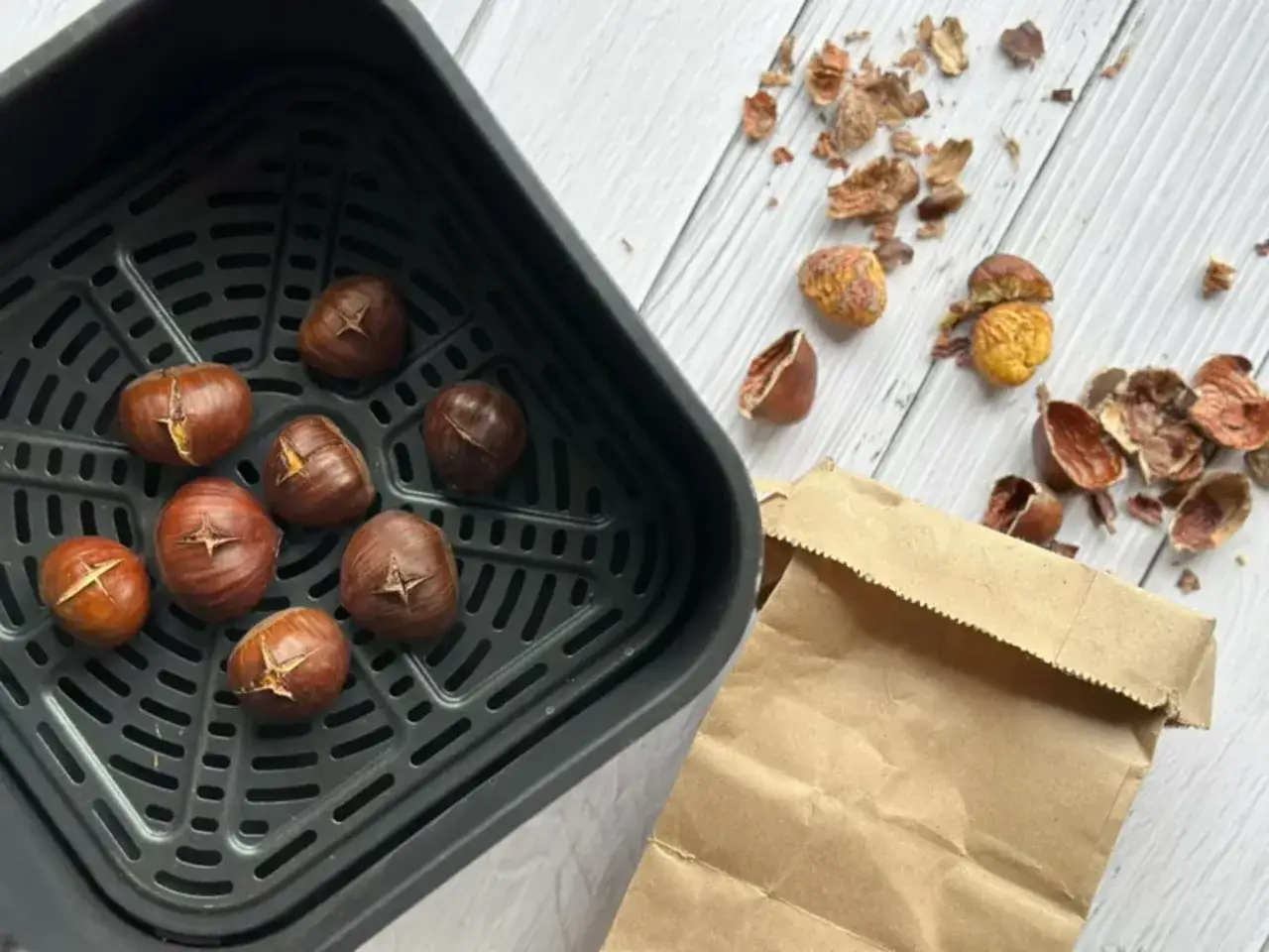 Ch&acirc;taignes grill&eacute;es dans un air fryer, pr&ecirc;tes &agrave; &ecirc;tre d&eacute;gust&eacute;es. Les coquilles vides jonchent la table.