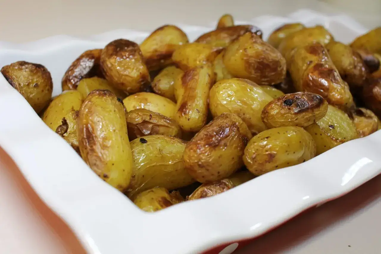 Un plat blanc rempli de pommes de terre sautées dorées et croustillantes, prêtes à être dégustées.