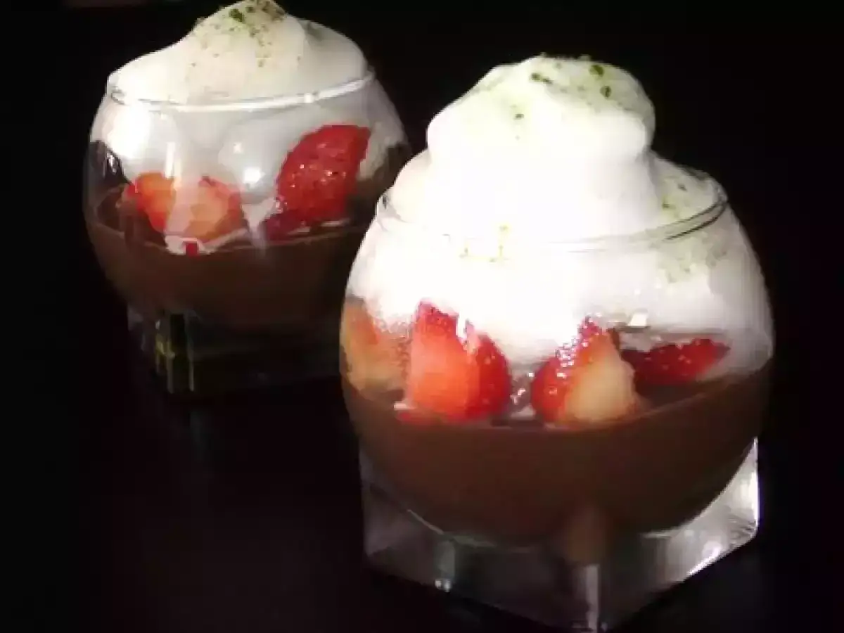 Deux verrines de recette mousse au chocolat au lait, garnies de fraises et surmontées d'une chantilly aérienne saupoudrée d'herbes.