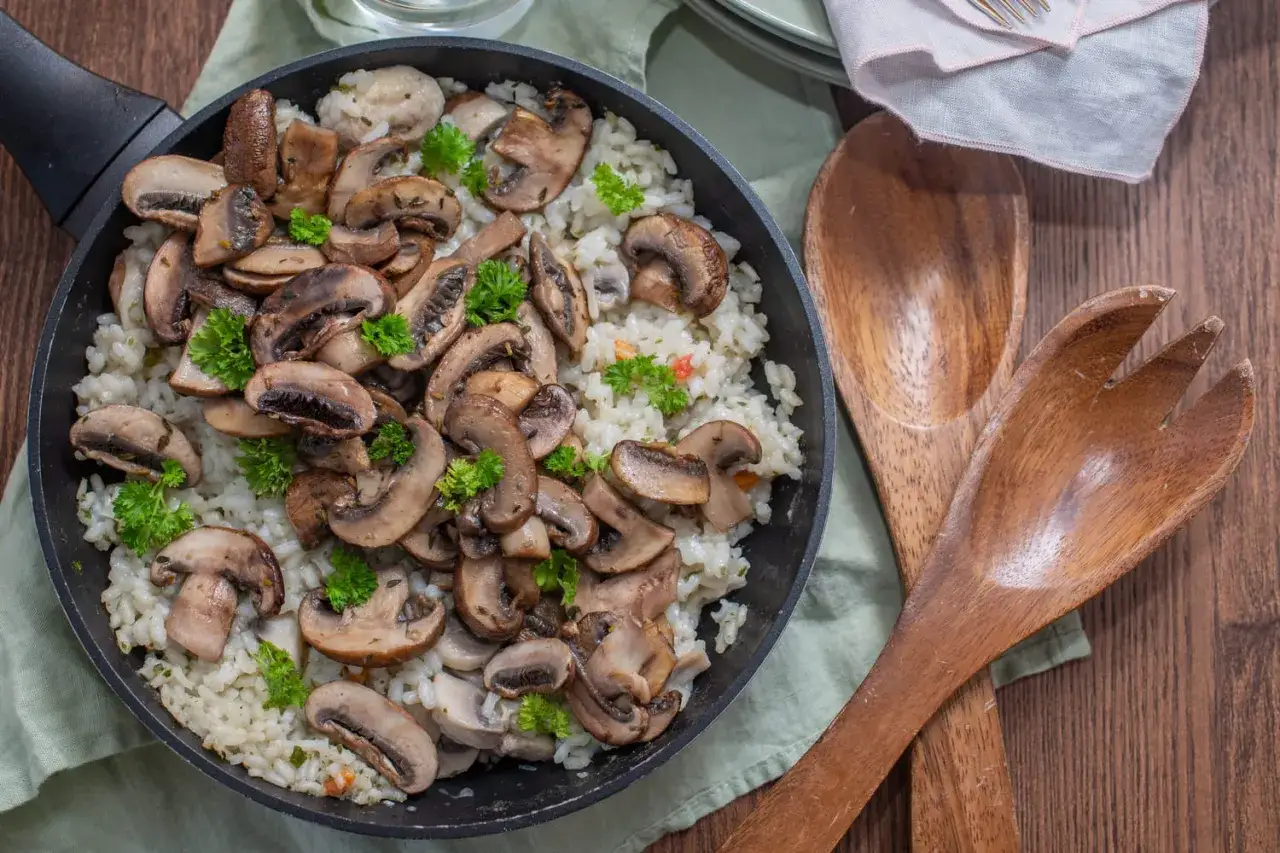 Risotto crémeux aux champignons de Paris, garni de persil frais. Une recette simple et savoureuse prête à être dégustée.