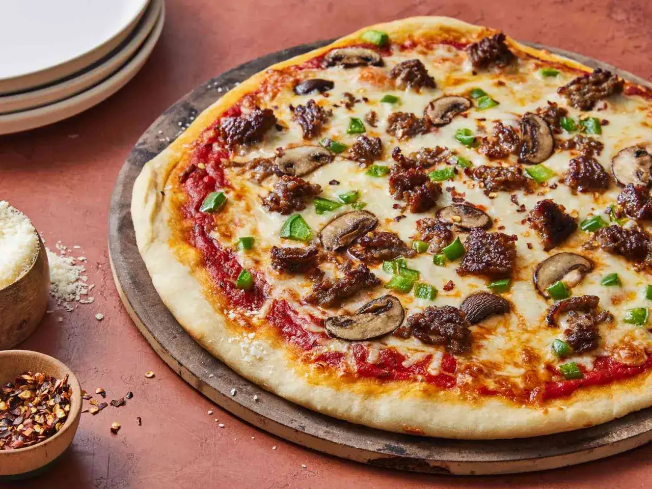 Pizza garnie de viande, champignons et poivrons verts sur une pâte à pizza fine et croustillante.
