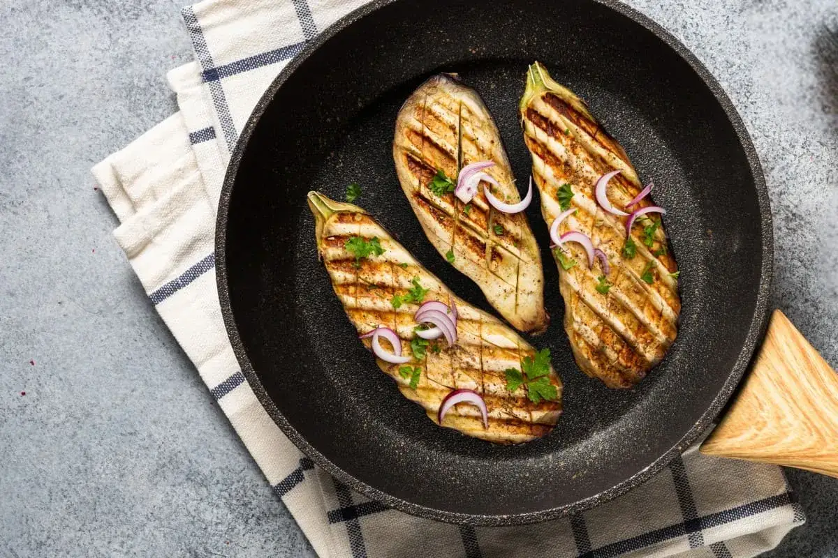 Aubergines grill&eacute;es &agrave; la po&ecirc;le, garnies d'oignons rouges et de persil. Une d&eacute;licieuse recette aubergine po&ecirc;le pr&ecirc;te &agrave; &ecirc;tre d&eacute;gust&eacute;e.