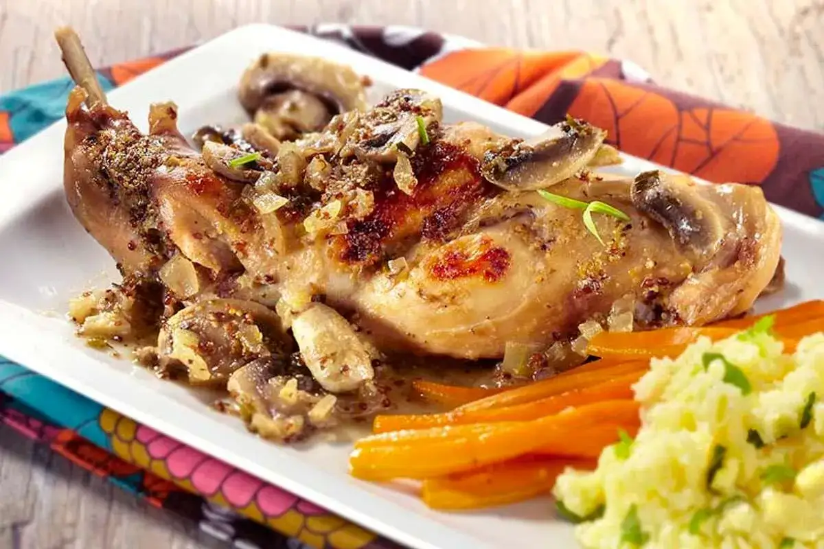 Un savoureux lapin au four, garni de champignons et d'oignons, servi avec des carottes et une purée crémeuse.