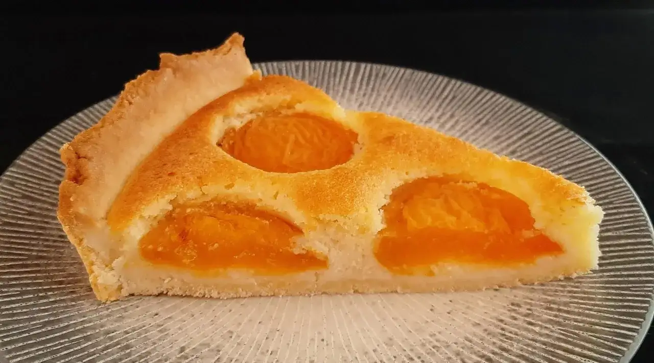 Tranche de tarte aux abricots classique, avec sa p&acirc;te dor&eacute;e et ses fruits juteux, pr&ecirc;te &agrave; &ecirc;tre d&eacute;gust&eacute;e.