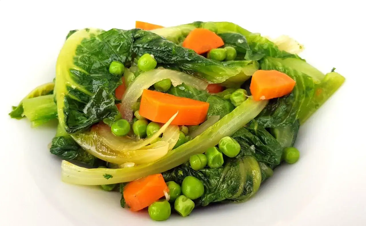 Un plat color&eacute; de jardini&egrave;re de l&eacute;gumes, avec des carottes, des petits pois et des feuilles vertes tendres.
