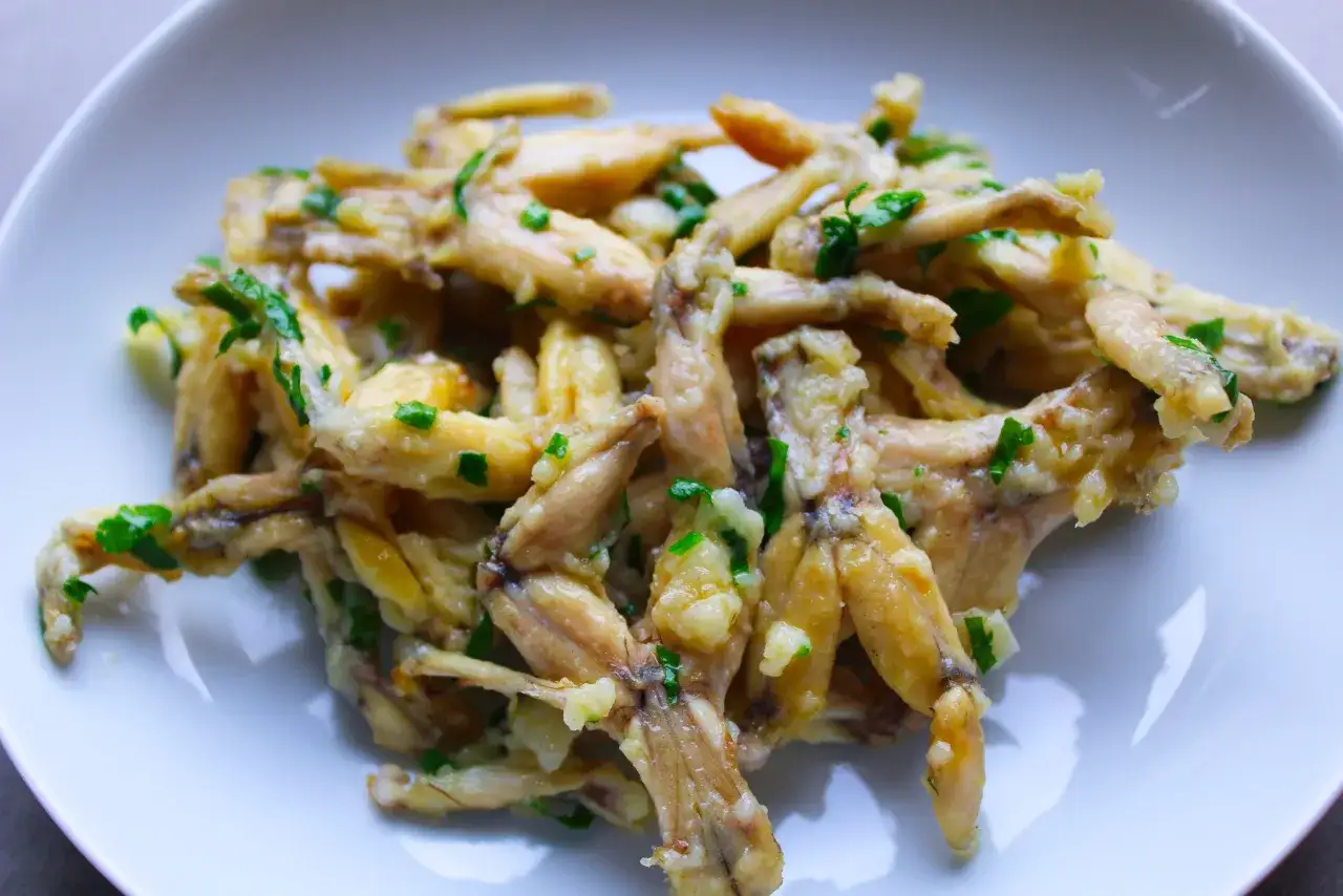 Un plat de cuisse de grenouille po&ecirc;l&eacute;e, garni de persil frais et d'ail. Un d&eacute;lice croustillant et savoureux.