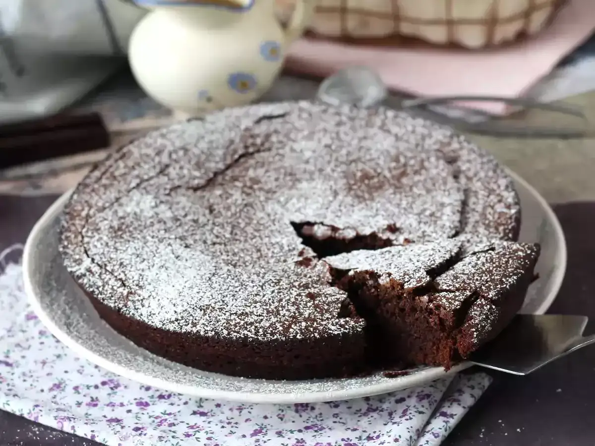 Un d&eacute;licieux g&acirc;teau au chocolat saupoudr&eacute; de sucre glace, parfait pour une recette g&acirc;teau au chocolat facile. Une part est d&eacute;j&agrave; servie.