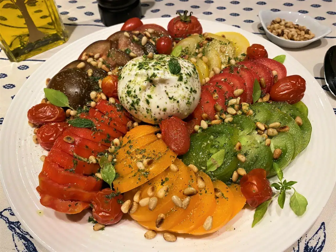 Une magnifique salade de tomates multicolores avec une burrata cr&eacute;meuse, des pignons de pin grill&eacute;s et des herbes fra&icirc;ches. Un d&eacute;lice estival.