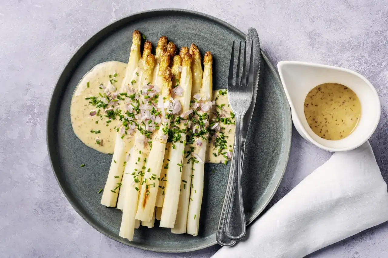 Asperges blanches nappées d'une sauce crémeuse, garnies de ciboulette et d'échalotes. Un délice printanier !